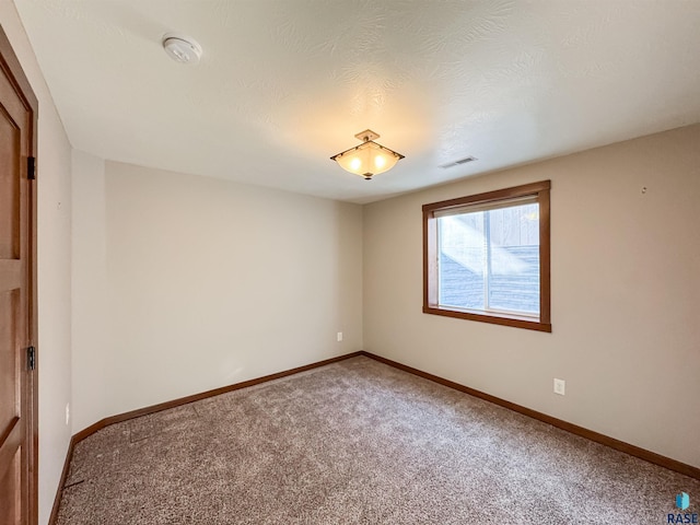 carpeted empty room featuring a textured ceiling