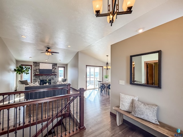 interior space featuring vaulted ceiling, wood-type flooring, a notable chandelier, and a textured ceiling