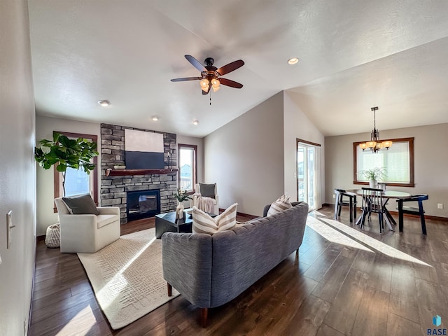 living room featuring lofted ceiling, a fireplace, ceiling fan with notable chandelier, and dark hardwood / wood-style flooring