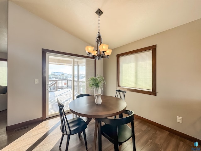 dining space with lofted ceiling, dark hardwood / wood-style floors, and a notable chandelier