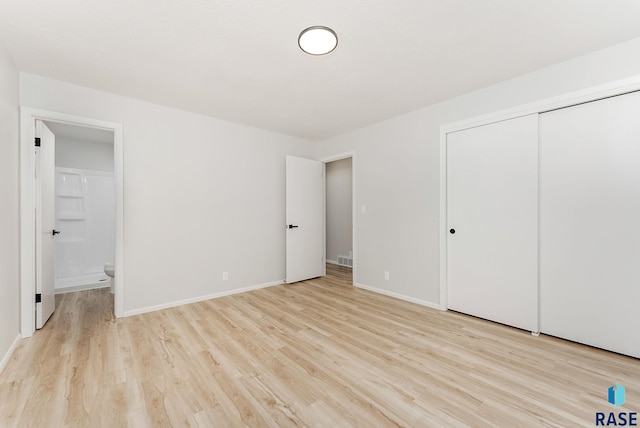 unfurnished bedroom featuring a closet, connected bathroom, and light hardwood / wood-style flooring