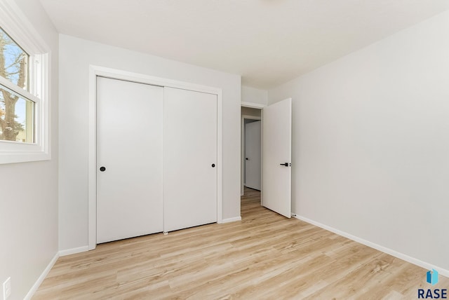 unfurnished bedroom with a closet and light wood-type flooring