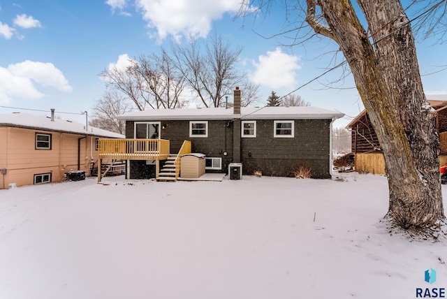 snow covered back of property featuring a deck and central air condition unit