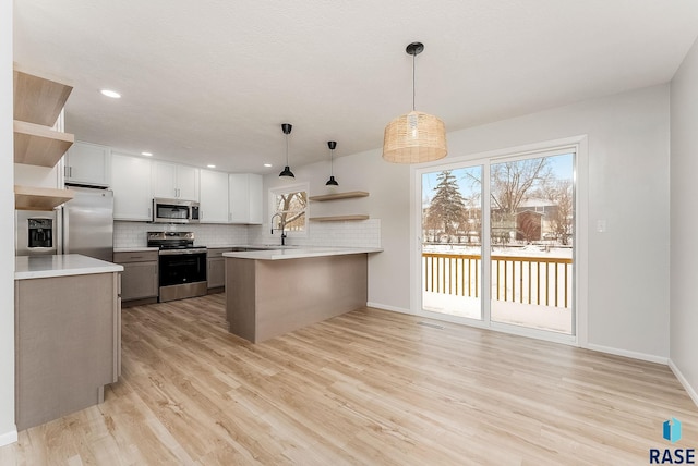 kitchen featuring hanging light fixtures, backsplash, stainless steel appliances, white cabinets, and kitchen peninsula