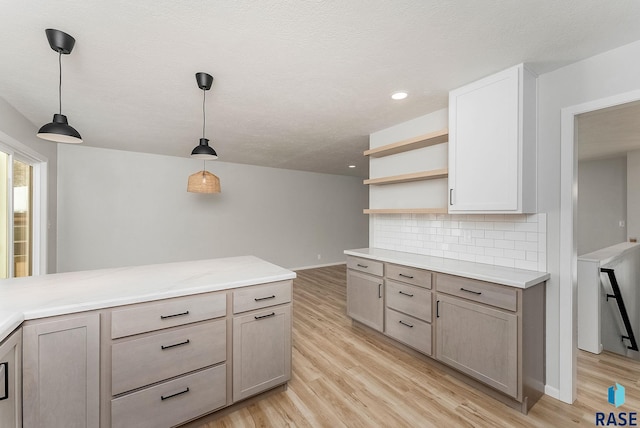 kitchen with tasteful backsplash, hanging light fixtures, light hardwood / wood-style flooring, and a textured ceiling