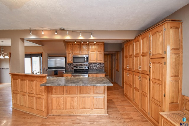 kitchen with a kitchen island, decorative light fixtures, backsplash, stainless steel appliances, and light hardwood / wood-style flooring