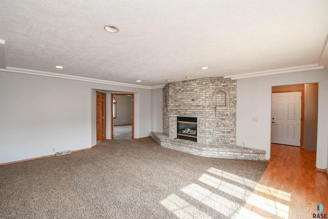 unfurnished living room with crown molding, a fireplace, and a textured ceiling