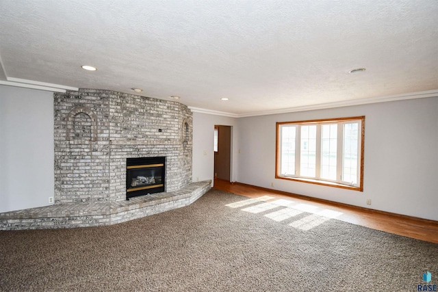 unfurnished living room with ornamental molding, carpet, a fireplace, and a textured ceiling