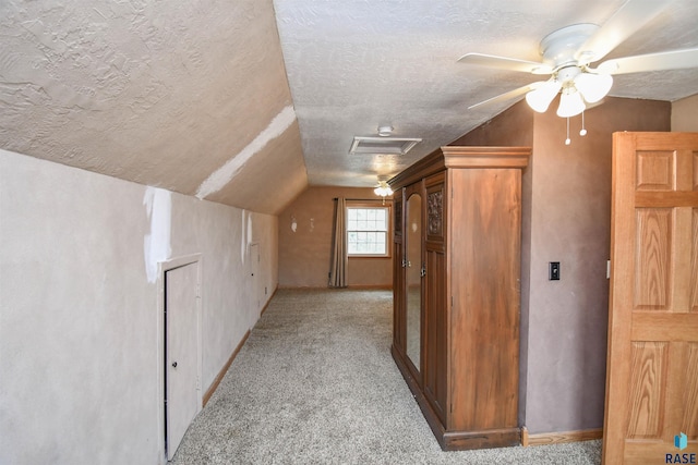 additional living space featuring vaulted ceiling, light colored carpet, ceiling fan, and a textured ceiling