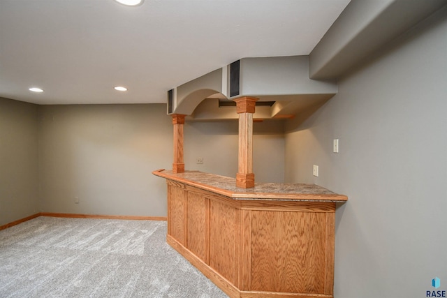 bar featuring decorative columns and light colored carpet