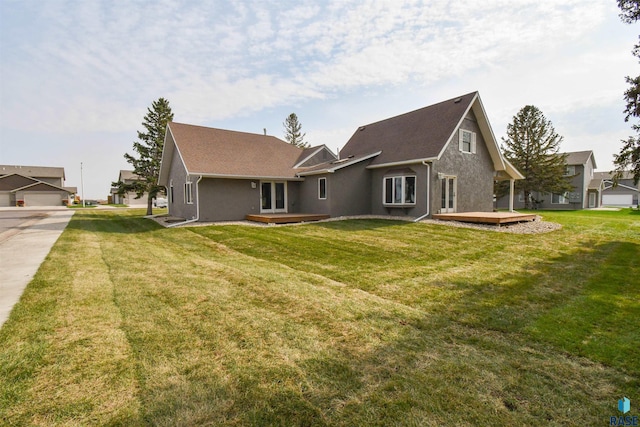 back of property with a wooden deck and a lawn