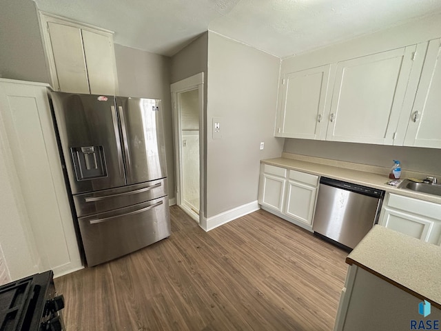 kitchen with wood-type flooring, appliances with stainless steel finishes, sink, and white cabinets