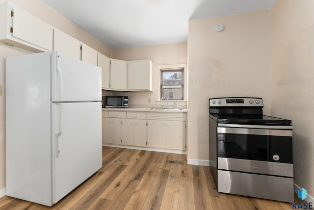 kitchen featuring white cabinetry, sink, stainless steel range with electric stovetop, white fridge, and light hardwood / wood-style floors