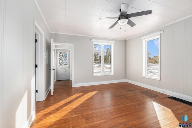 empty room featuring hardwood / wood-style flooring, ornamental molding, and ceiling fan