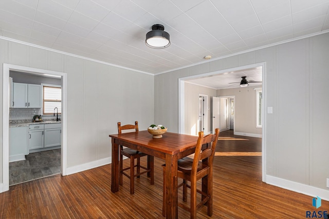 dining area featuring dark wood-type flooring, ceiling fan, ornamental molding, and sink