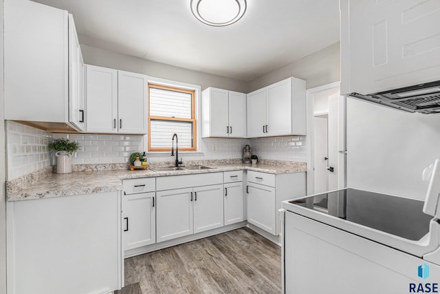 kitchen with sink, light hardwood / wood-style flooring, white cabinets, white range with electric stovetop, and backsplash