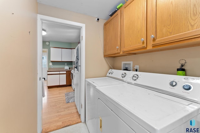 laundry room with light hardwood / wood-style floors, cabinets, and washing machine and clothes dryer