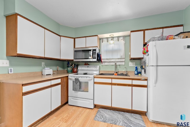 kitchen with sink, white appliances, light hardwood / wood-style flooring, and white cabinets