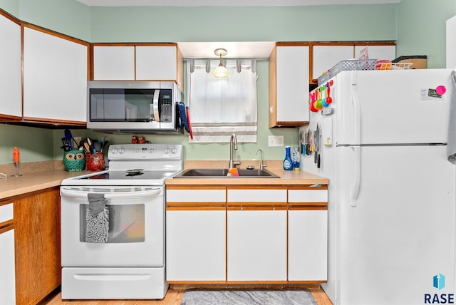 kitchen featuring white cabinetry, sink, and white appliances