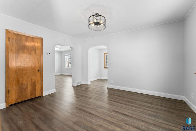 spare room featuring dark hardwood / wood-style flooring and a notable chandelier