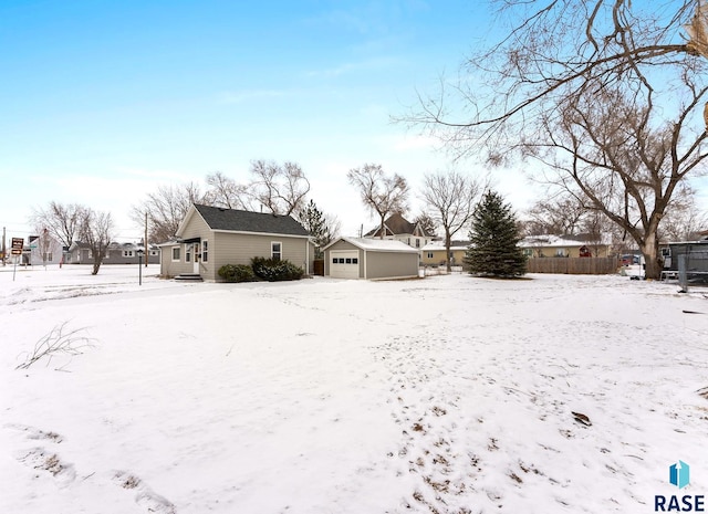 yard layered in snow featuring a garage and an outdoor structure