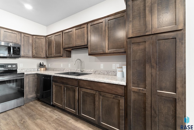 kitchen featuring sink, light stone counters, light hardwood / wood-style floors, stainless steel appliances, and dark brown cabinets