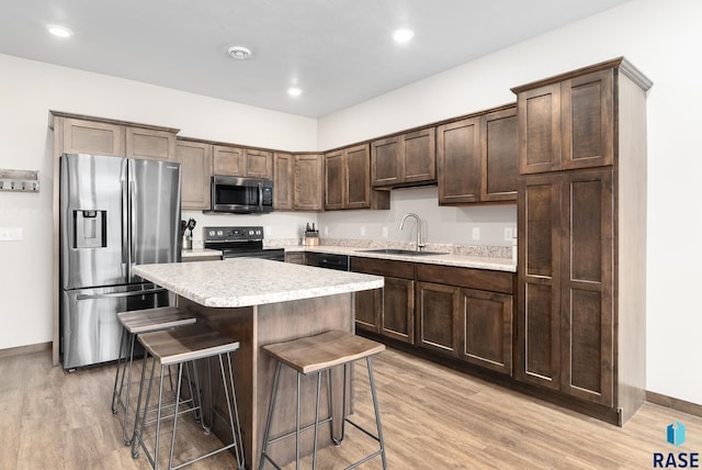 kitchen featuring a breakfast bar, sink, a center island, dark brown cabinetry, and stainless steel appliances