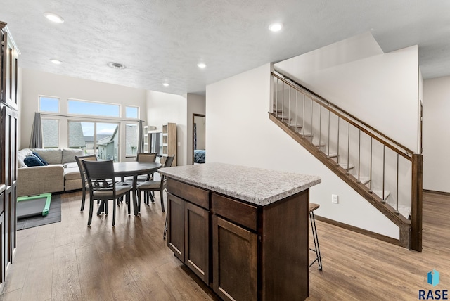 kitchen featuring a kitchen island, a breakfast bar, light wood-type flooring, and dark brown cabinets