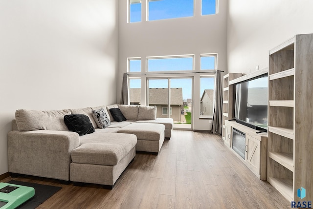 living room featuring hardwood / wood-style flooring, a high ceiling, and a healthy amount of sunlight