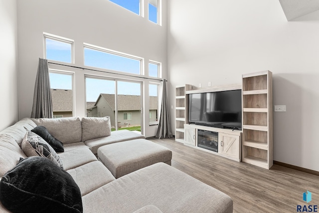 living room featuring a towering ceiling, a wealth of natural light, and light wood-type flooring