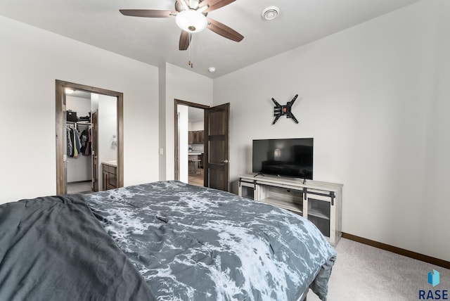 bedroom with a walk in closet, light carpet, and ceiling fan