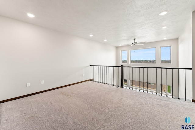 empty room featuring ceiling fan, carpet, and a textured ceiling