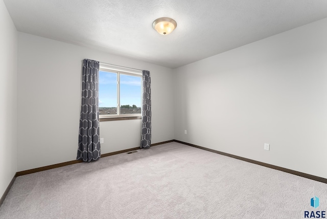 empty room with carpet floors and a textured ceiling