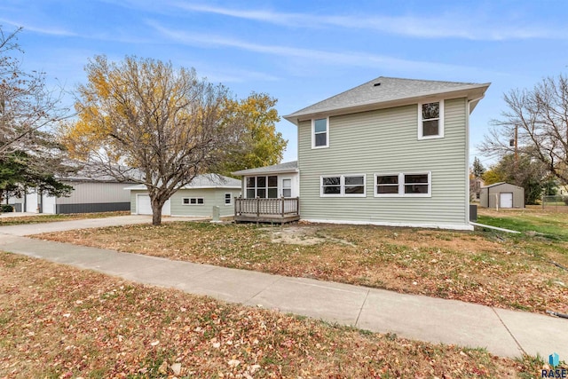 front facade featuring a deck, a front lawn, and a storage unit