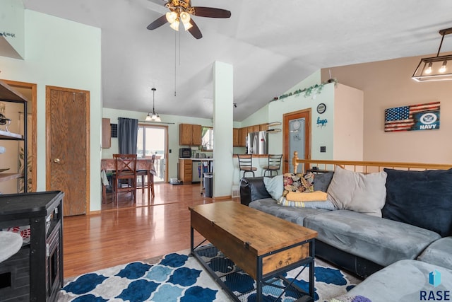 living room with hardwood / wood-style flooring, ceiling fan, and vaulted ceiling