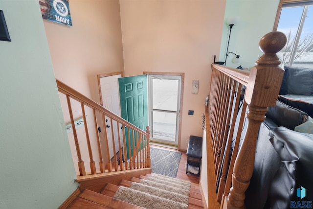 staircase with a towering ceiling and wood-type flooring