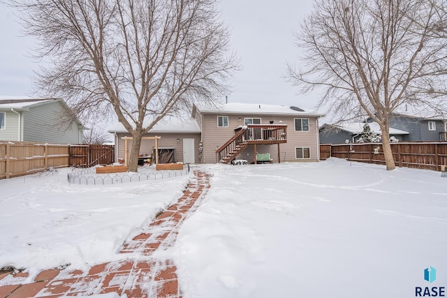 snow covered rear of property with a wooden deck