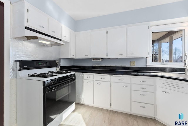 kitchen with gas range, light wood-type flooring, decorative backsplash, and white cabinets