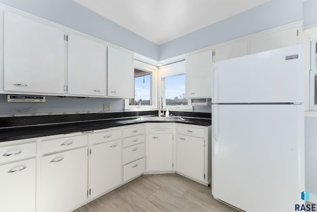 kitchen featuring white refrigerator, white cabinetry, and sink