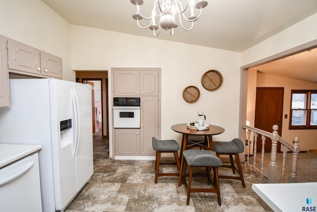 kitchen featuring hanging light fixtures, white appliances, vaulted ceiling, and a chandelier