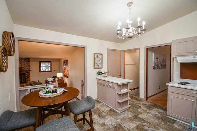 dining space featuring an inviting chandelier, a brick fireplace, and vaulted ceiling