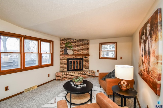 carpeted living room featuring a brick fireplace and a textured ceiling