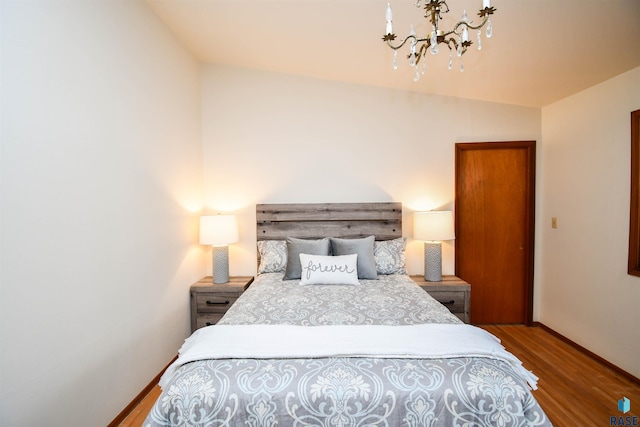 bedroom with wood-type flooring and a notable chandelier