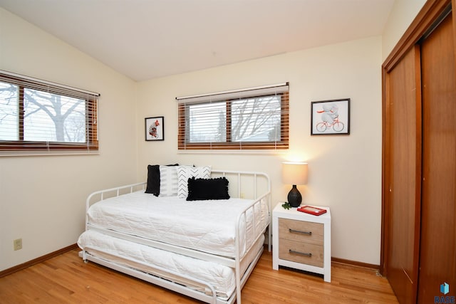 bedroom featuring multiple windows, lofted ceiling, and light hardwood / wood-style floors