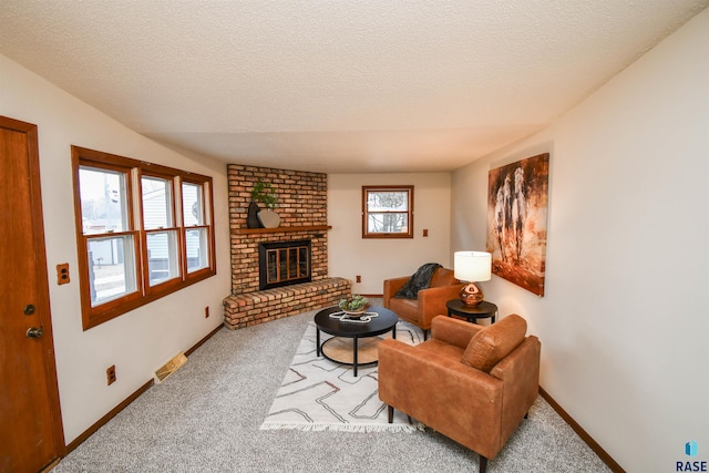 living room with a brick fireplace, carpet, and a textured ceiling