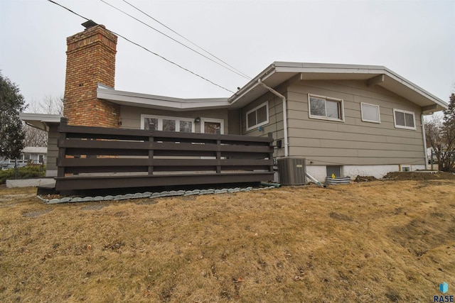 rear view of property with central AC and a lawn