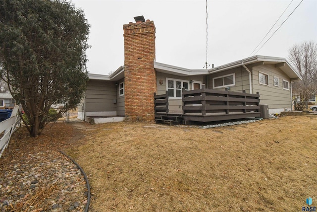 rear view of property featuring a wooden deck, central AC, and a lawn