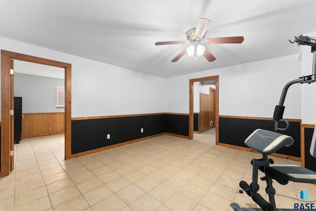 exercise area with wooden walls and ceiling fan