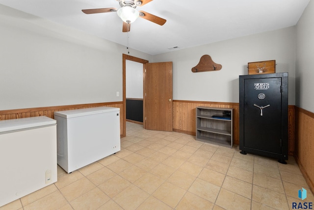 interior space with wood walls, ceiling fan, and refrigerator