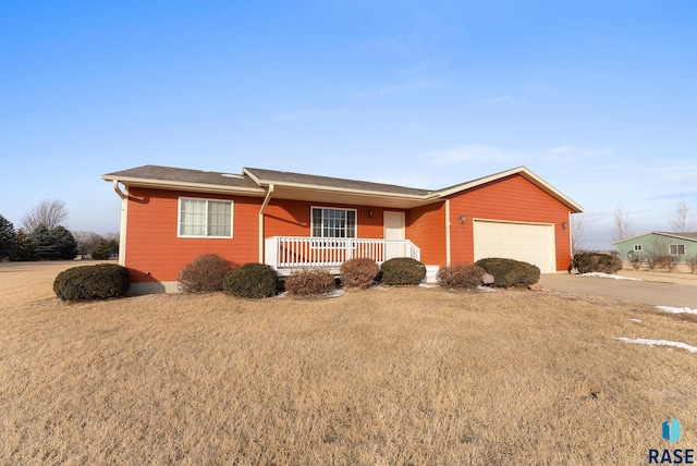 ranch-style home featuring a garage, covered porch, and a front yard